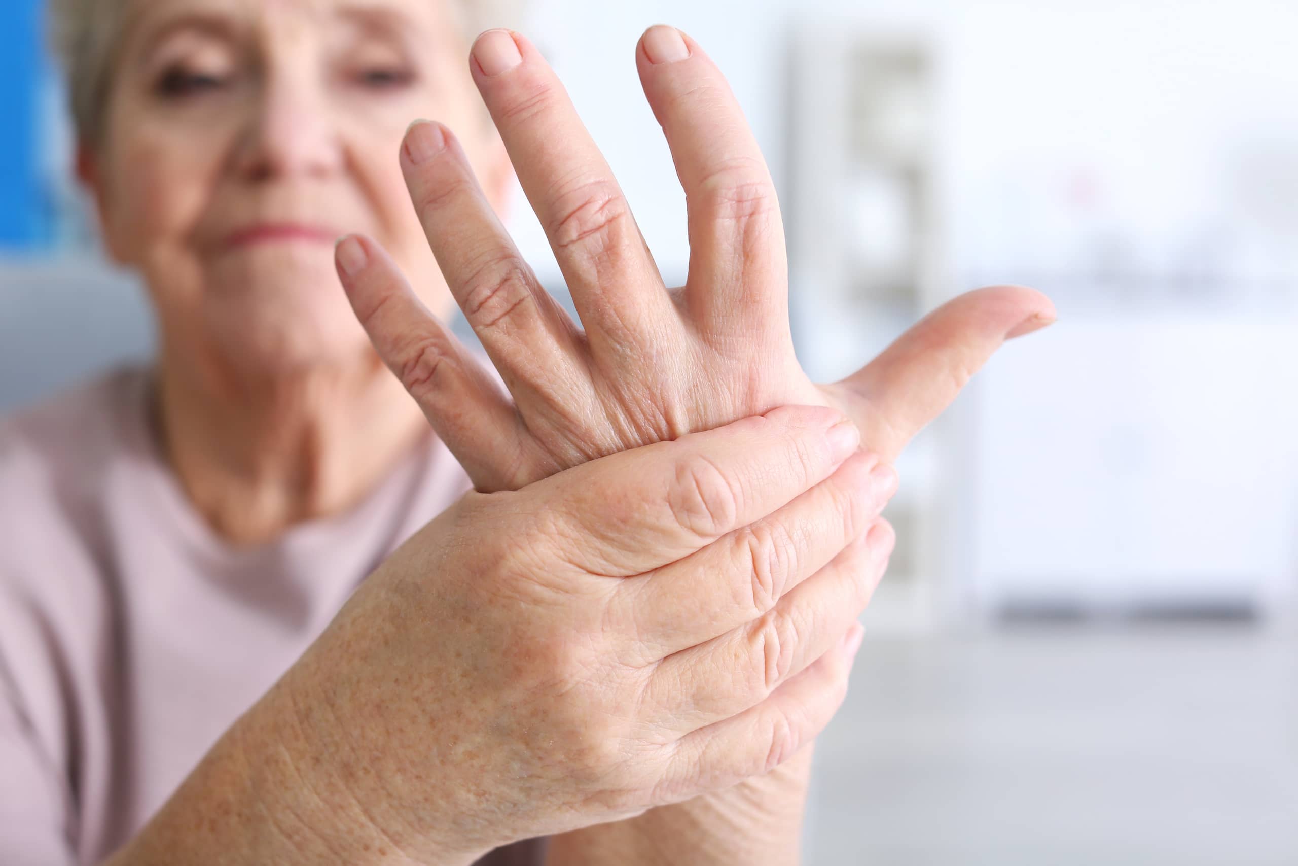 older adult gripping her sore hand because of arthritis