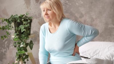 woman with lower back pain holding her back