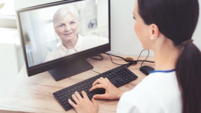 Therapist videoconferencing with patient on computer