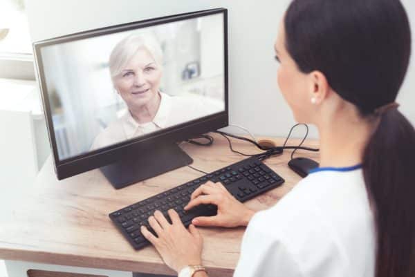 Therapist videoconferencing with patient on computer